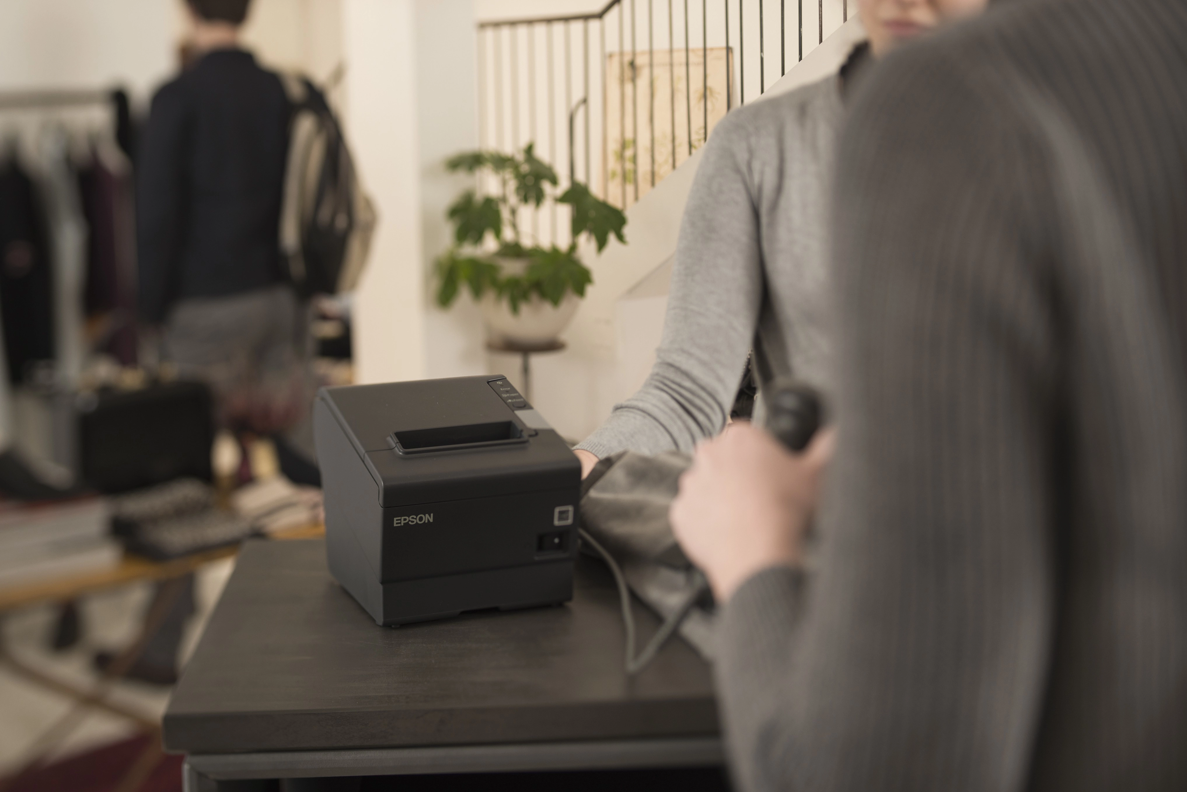 Epson TM-T88V thermal receipt printer in use at a retail checkout, compatible with Epson 152382501 roll paper stopper replacement part.