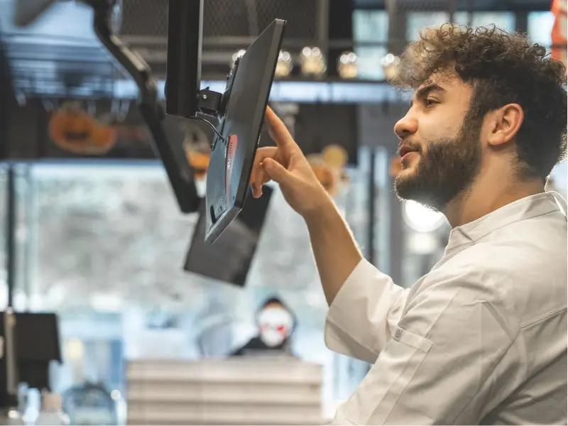 Junger Koch tippt auf Touchscreen in Profiküche