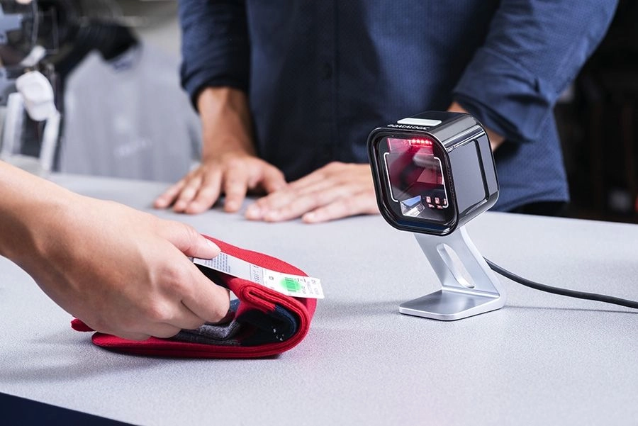 Datalogic Magellan 1500i black USB presentation scanner reading a clothing barcode at a POS checkout counter